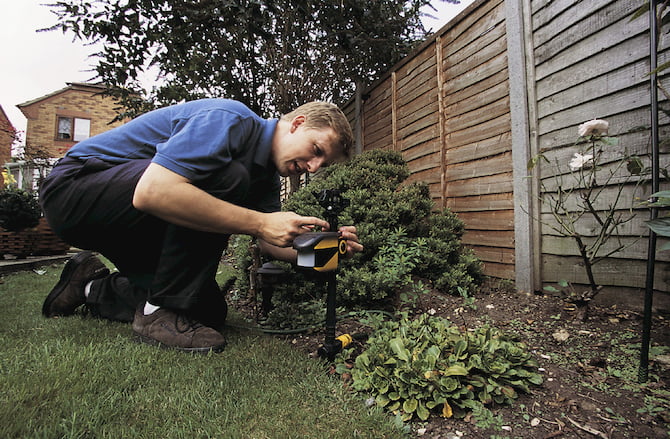 man installing a cat deterrent in the garden