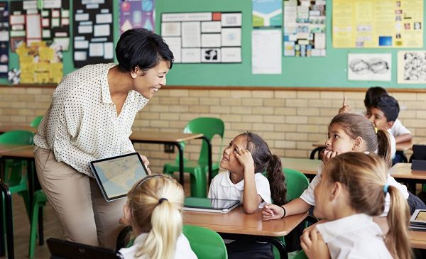 Teacher interacting with kids in class with tablet