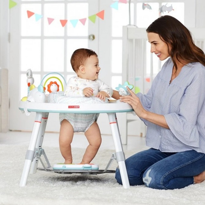 picture of a mother beside a baby in activity centre on a rug 