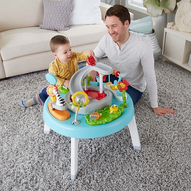 picture of a man beside a baby in front a baby activity centre on a rug in the living room