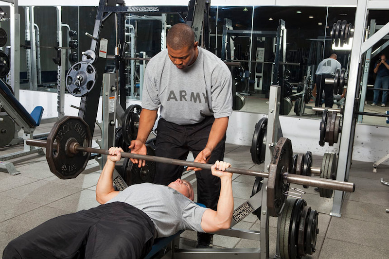 Man lifting barbell with second person who acts as a spotter