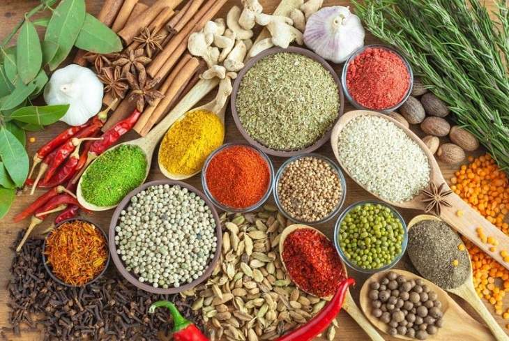 dried herbs, spices and other pantry essentials in spoons on wooden table 