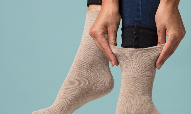 picture of person putting on diabetic compression socks in front a blue background  