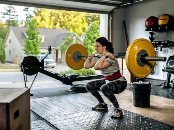 Women exercising with barbells in a home gym