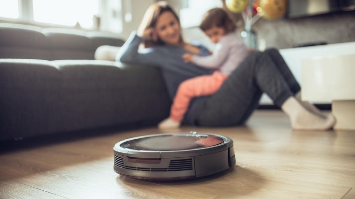 Close-up of mother and a kid watching a robotic vacuum cleaner