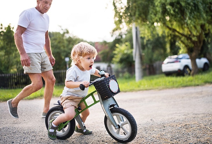 picture of a person beside a kid on a balance bike
