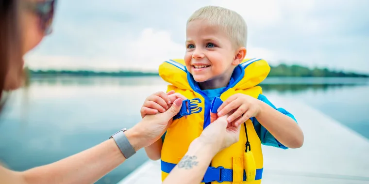 mom putting a child life jacket on her kid