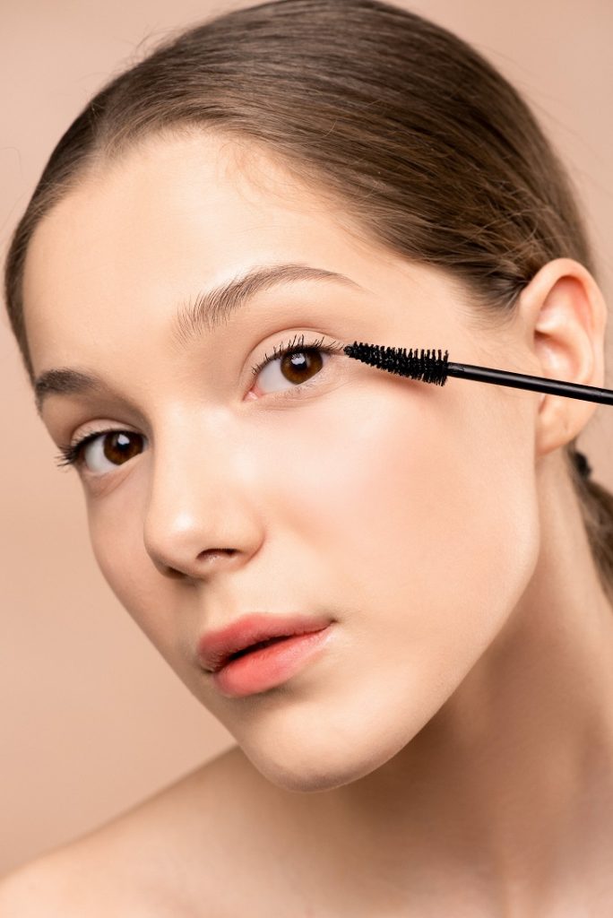 A mascara wand next to an eye