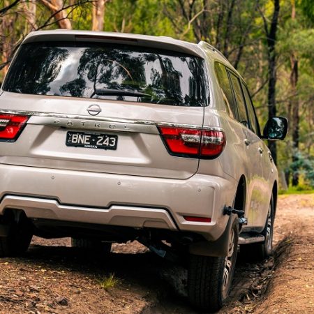 White Nissan Y62 Patrol driven in nature